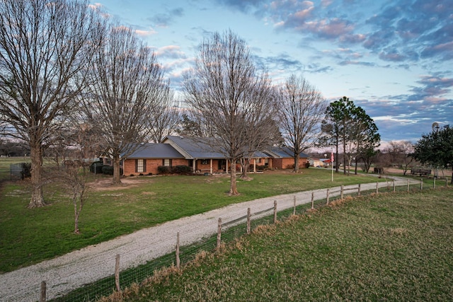 ranch-style home featuring brick siding, fence, and a front lawn