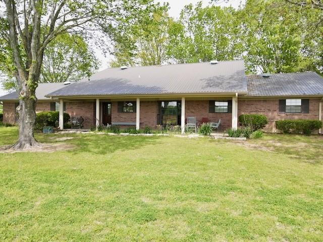 back of house with brick siding and a lawn