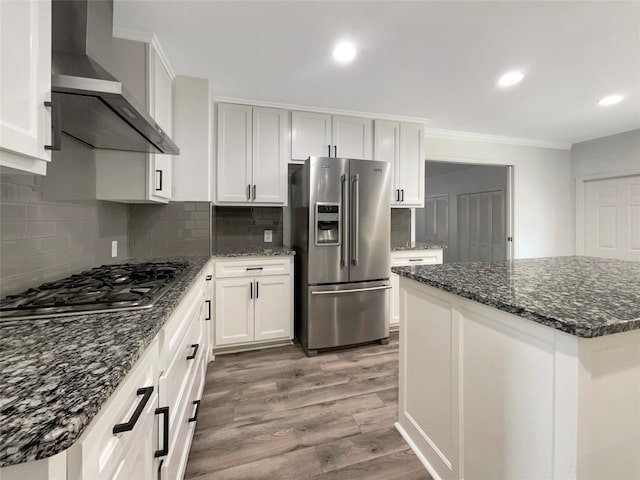 kitchen with wood-type flooring, wall chimney exhaust hood, tasteful backsplash, white cabinetry, and stainless steel appliances