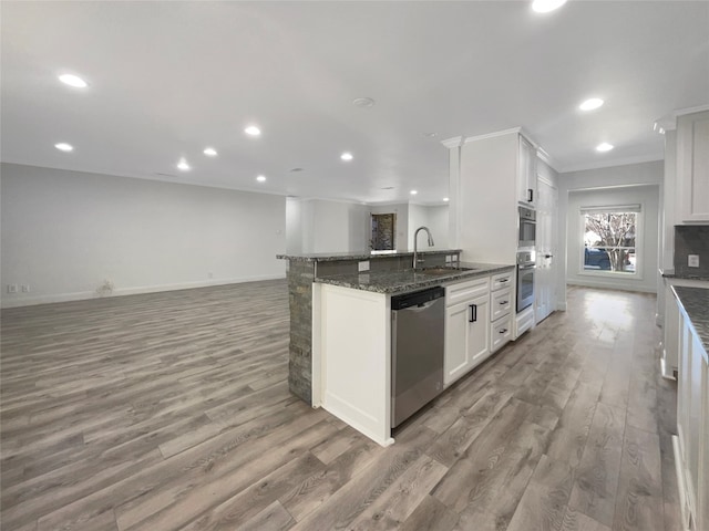 kitchen with wood-type flooring, white cabinetry, dark stone counters, and stainless steel appliances