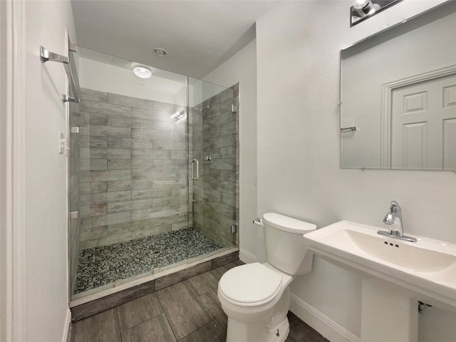 bathroom featuring hardwood / wood-style floors, sink, toilet, and a shower with shower door