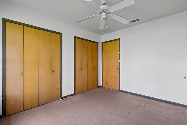 unfurnished bedroom featuring multiple closets, light colored carpet, and ceiling fan