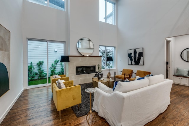 living room with a fireplace, a high ceiling, and dark wood-type flooring