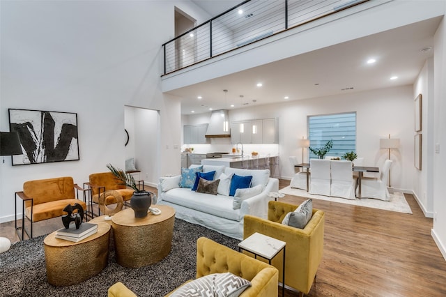 living room featuring light hardwood / wood-style flooring, a high ceiling, and sink