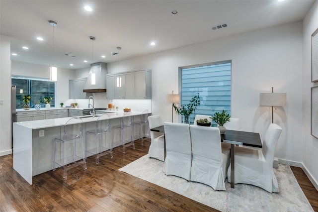 kitchen featuring a center island with sink, gray cabinets, dark hardwood / wood-style flooring, and hanging light fixtures