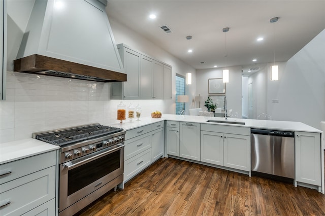 kitchen with kitchen peninsula, custom range hood, appliances with stainless steel finishes, and sink