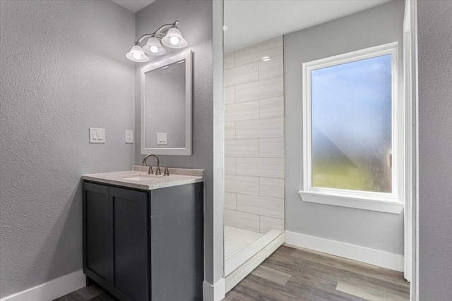 bathroom with a healthy amount of sunlight, large vanity, walk in shower, and hardwood / wood-style flooring