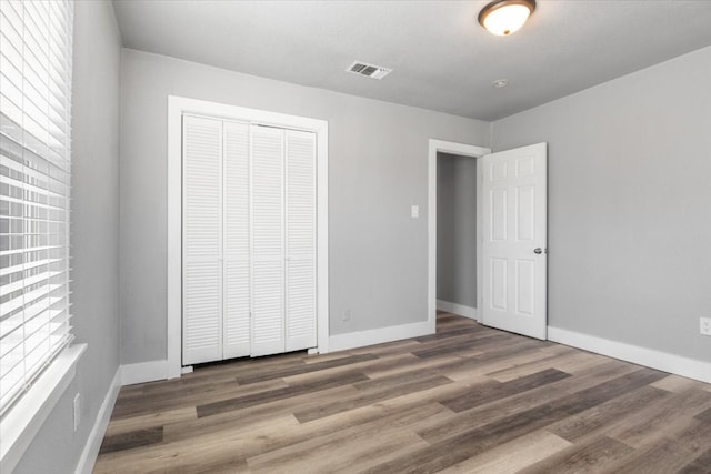 unfurnished bedroom featuring a closet and dark wood-type flooring