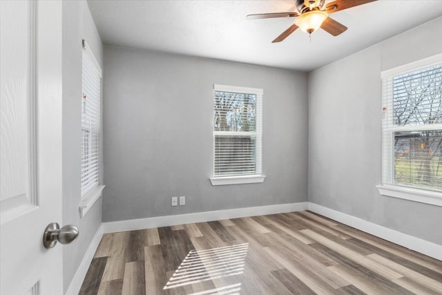 empty room with wood-type flooring, ceiling fan, and a healthy amount of sunlight