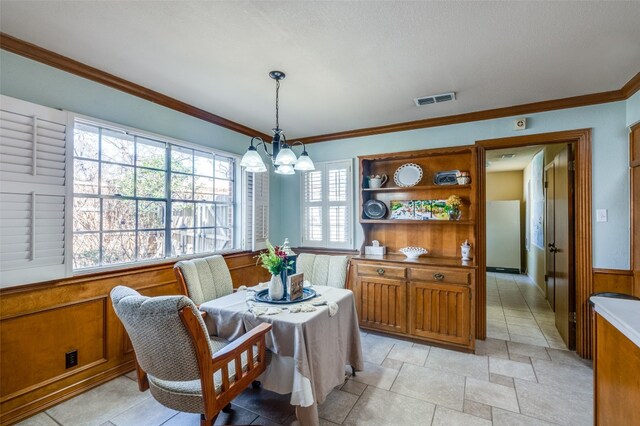 tiled dining area featuring a notable chandelier and crown molding