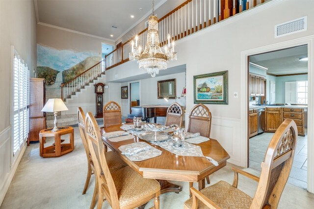 carpeted dining space with a chandelier, a towering ceiling, and crown molding