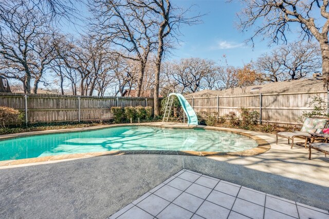 view of swimming pool with a water slide and a patio area