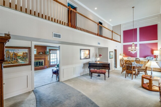 interior space featuring a chandelier, ornamental molding, a high ceiling, and a fireplace