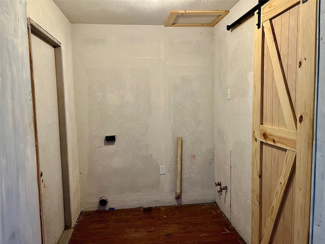 clothes washing area featuring a barn door and dark hardwood / wood-style floors