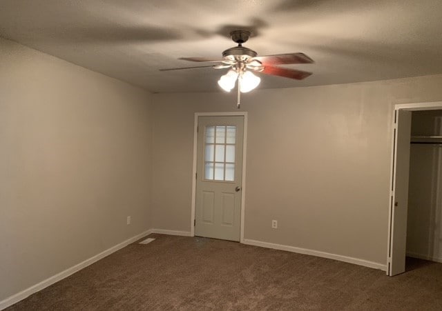 unfurnished bedroom with dark colored carpet and ceiling fan