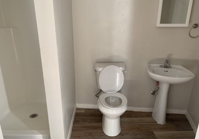 bathroom featuring a shower, toilet, and hardwood / wood-style floors