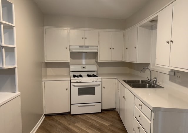 kitchen with white gas range, sink, dark wood-type flooring, and white cabinets