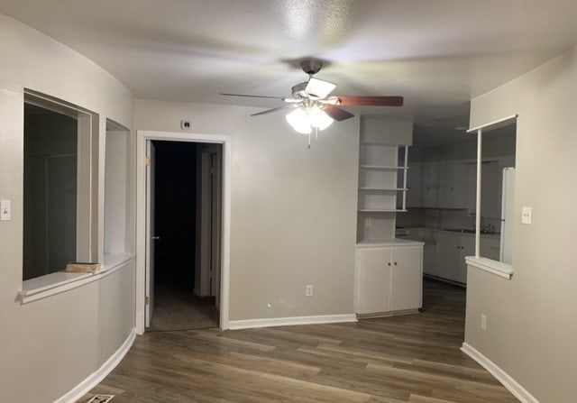 empty room with ceiling fan and dark hardwood / wood-style flooring