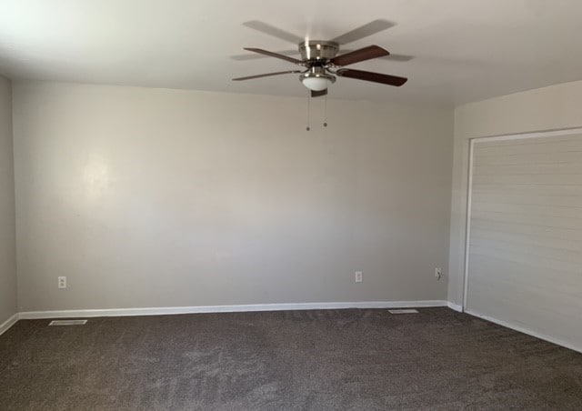 unfurnished room with ceiling fan and dark colored carpet