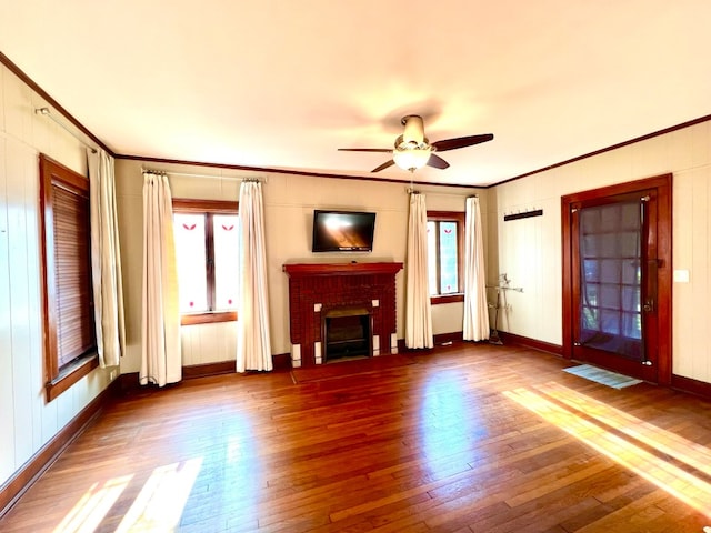 unfurnished living room with ornamental molding, ceiling fan, dark wood-type flooring, and a fireplace