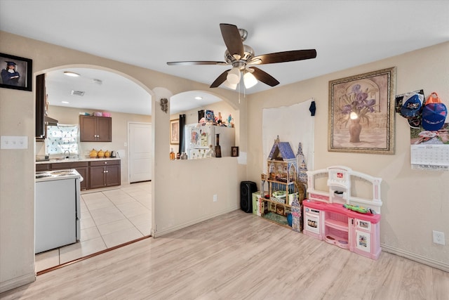 rec room with sink, light hardwood / wood-style flooring, and ceiling fan