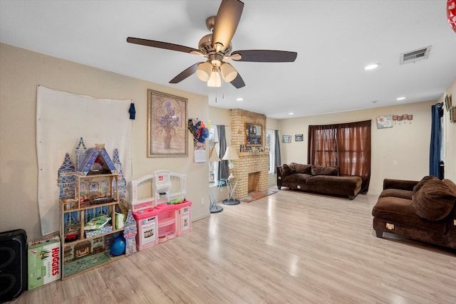 playroom with light hardwood / wood-style floors, brick wall, and ceiling fan