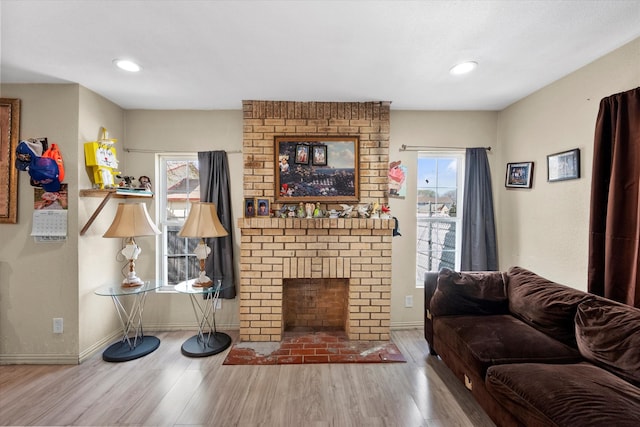 living room featuring brick wall, a brick fireplace, and hardwood / wood-style floors