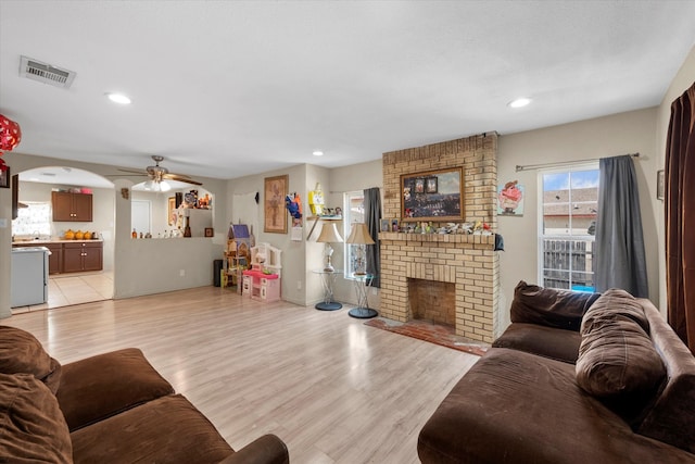 living room with a fireplace, ceiling fan, and light hardwood / wood-style floors