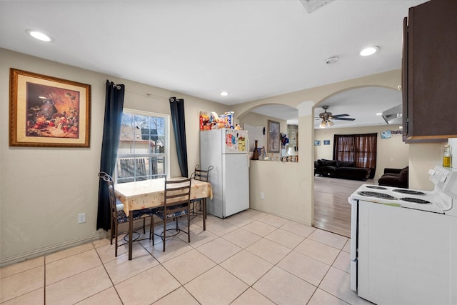 kitchen featuring dark brown cabinets, light tile patterned flooring, and white appliances