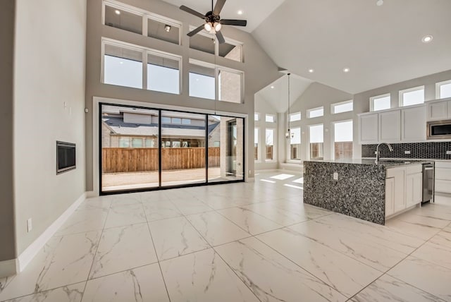 kitchen featuring marble finish floor, stainless steel microwave, stone counters, and decorative backsplash