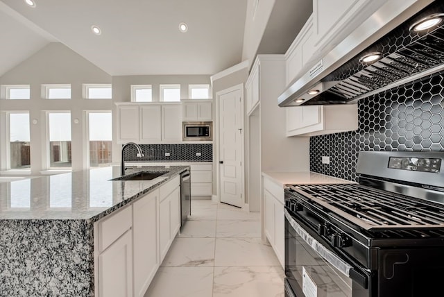 kitchen with stainless steel appliances, a sink, white cabinetry, marble finish floor, and wall chimney exhaust hood