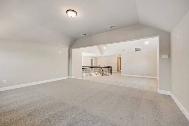 unfurnished room featuring baseboards, visible vents, and vaulted ceiling