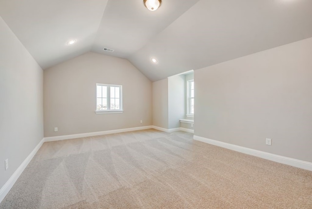 bonus room featuring vaulted ceiling, light carpet, visible vents, and baseboards