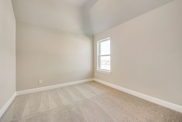 spare room featuring light carpet and baseboards