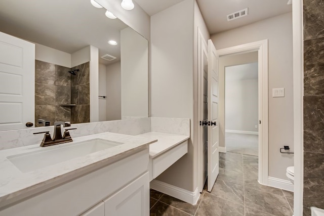 full bathroom with visible vents, toilet, a tile shower, vanity, and baseboards