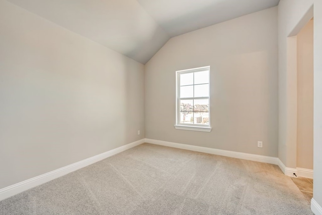 spare room with light carpet, baseboards, and lofted ceiling