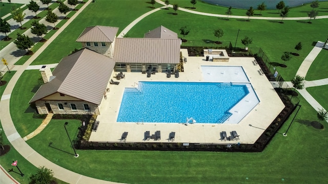 community pool with a patio, a yard, and fence