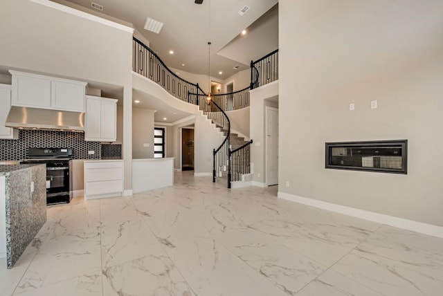 kitchen with electric range, baseboards, white cabinets, marble finish floor, and range hood