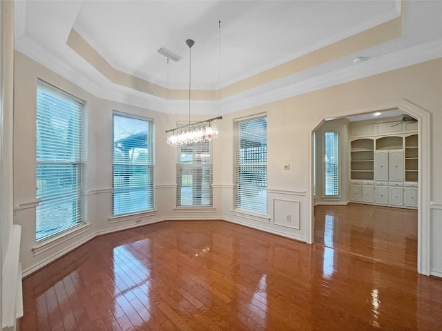 empty room featuring plenty of natural light, dark hardwood / wood-style floors, and a raised ceiling