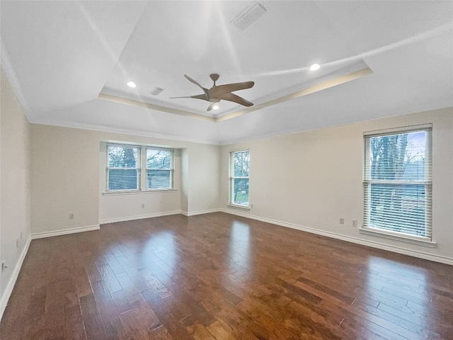 empty room with a tray ceiling, ornamental molding, ceiling fan, and dark hardwood / wood-style floors