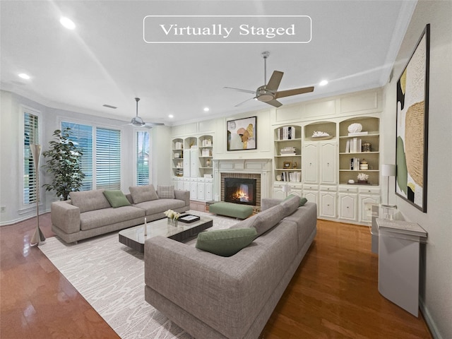 living room with light hardwood / wood-style floors, a brick fireplace, ceiling fan, and crown molding