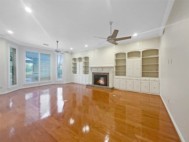 unfurnished living room with ceiling fan, a fireplace, and light hardwood / wood-style floors