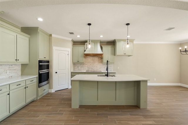 kitchen with backsplash, premium range hood, a chandelier, and a center island with sink