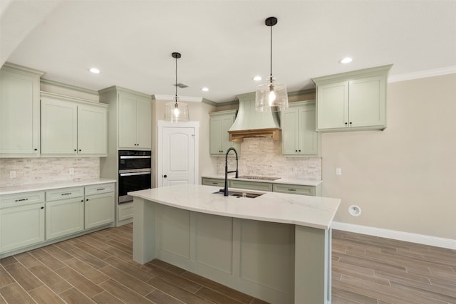 kitchen with an island with sink, pendant lighting, backsplash, double oven, and custom exhaust hood