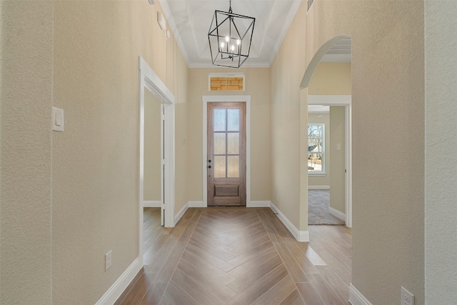 entrance foyer with an inviting chandelier, crown molding, and light parquet flooring