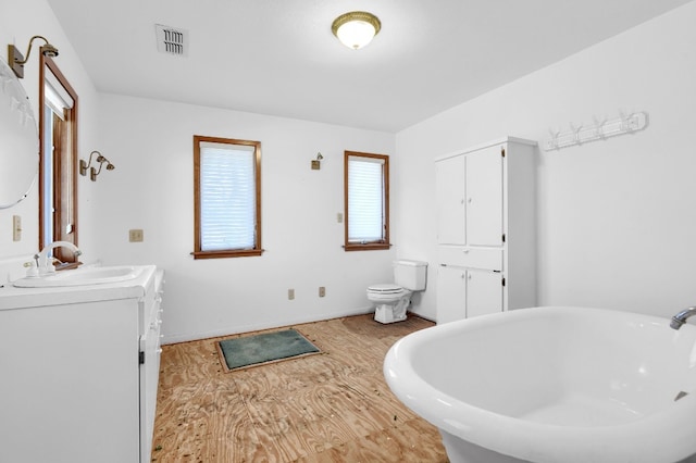 bathroom featuring a tub, toilet, and vanity with extensive cabinet space