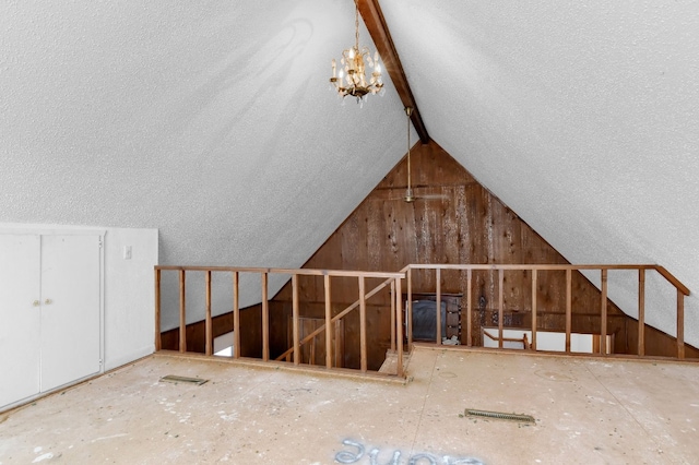 interior space with an inviting chandelier, a textured ceiling, and lofted ceiling