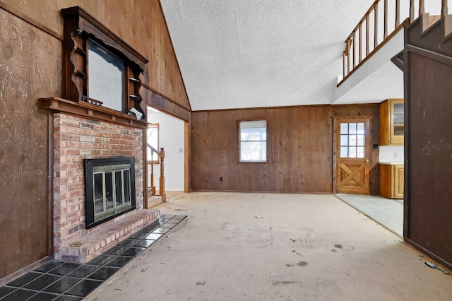 unfurnished living room featuring a textured ceiling, a fireplace, and wood walls