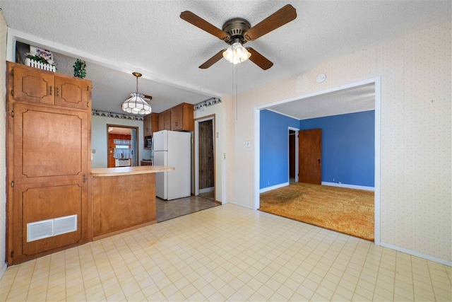 kitchen featuring light colored carpet, white fridge, ceiling fan, a textured ceiling, and hanging light fixtures