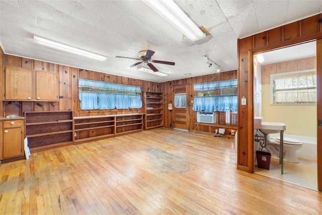 unfurnished room featuring wood walls, ceiling fan, and light hardwood / wood-style flooring